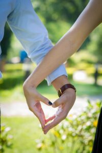 a man and woman slightly holding hands to make a heart with their hands